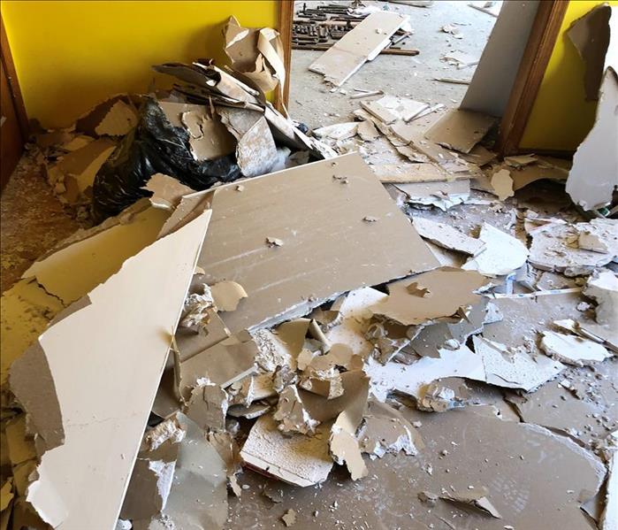 living room floor covered with pieces of ceiling and insulation