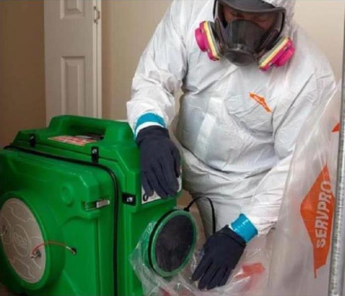 man in protective gear cleaning a room