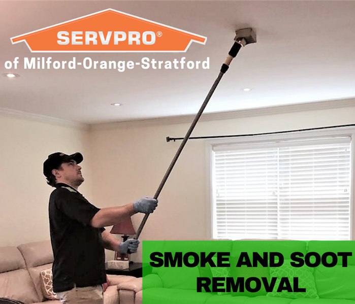 man cleaning soot off of a ceiling
