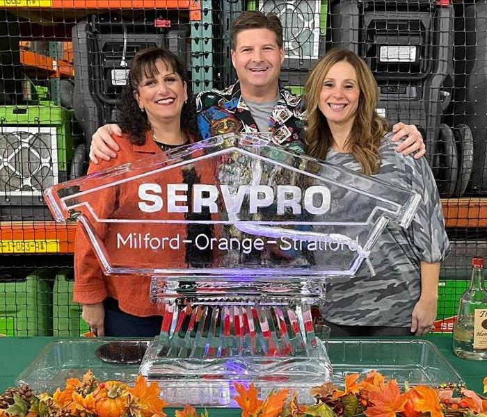 man and 2 women smiling in front of a servpro sculpture